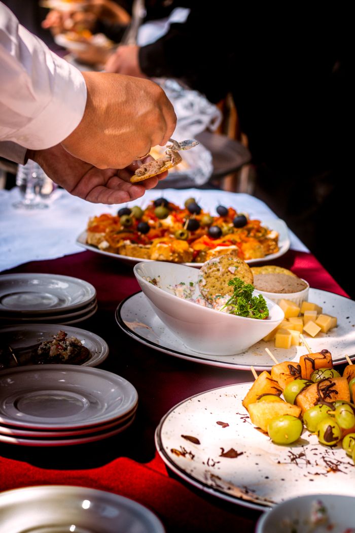 services-img Close-up of a buffet table with diverse appetizers, fruits, and cheese.
